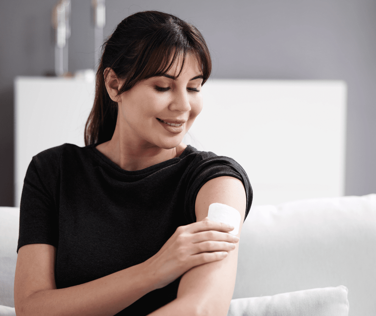 A woman is putting on an arm tattoo.