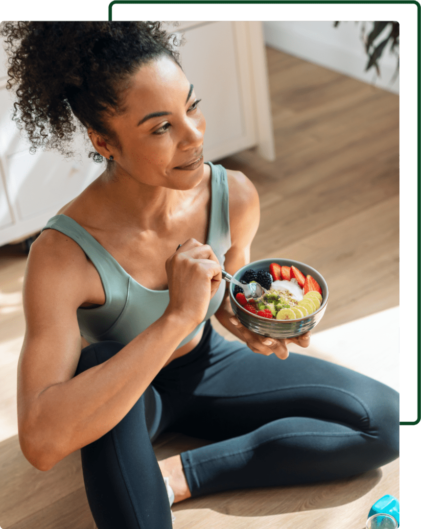 A woman sitting on the floor eating fruit.